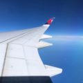 view over an airplane wing with the Delta logo on the wingtip, over the Pacific Ocean