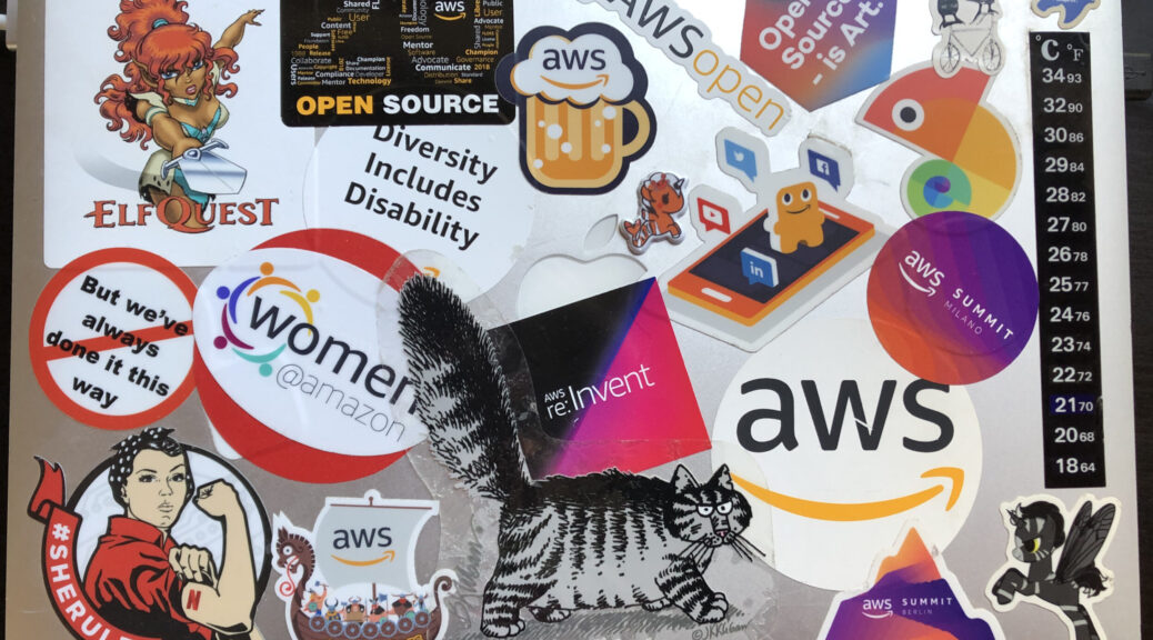 a Mac laptop covered in stickers, many for AWS events
