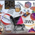 a Mac laptop covered in stickers, many for AWS events