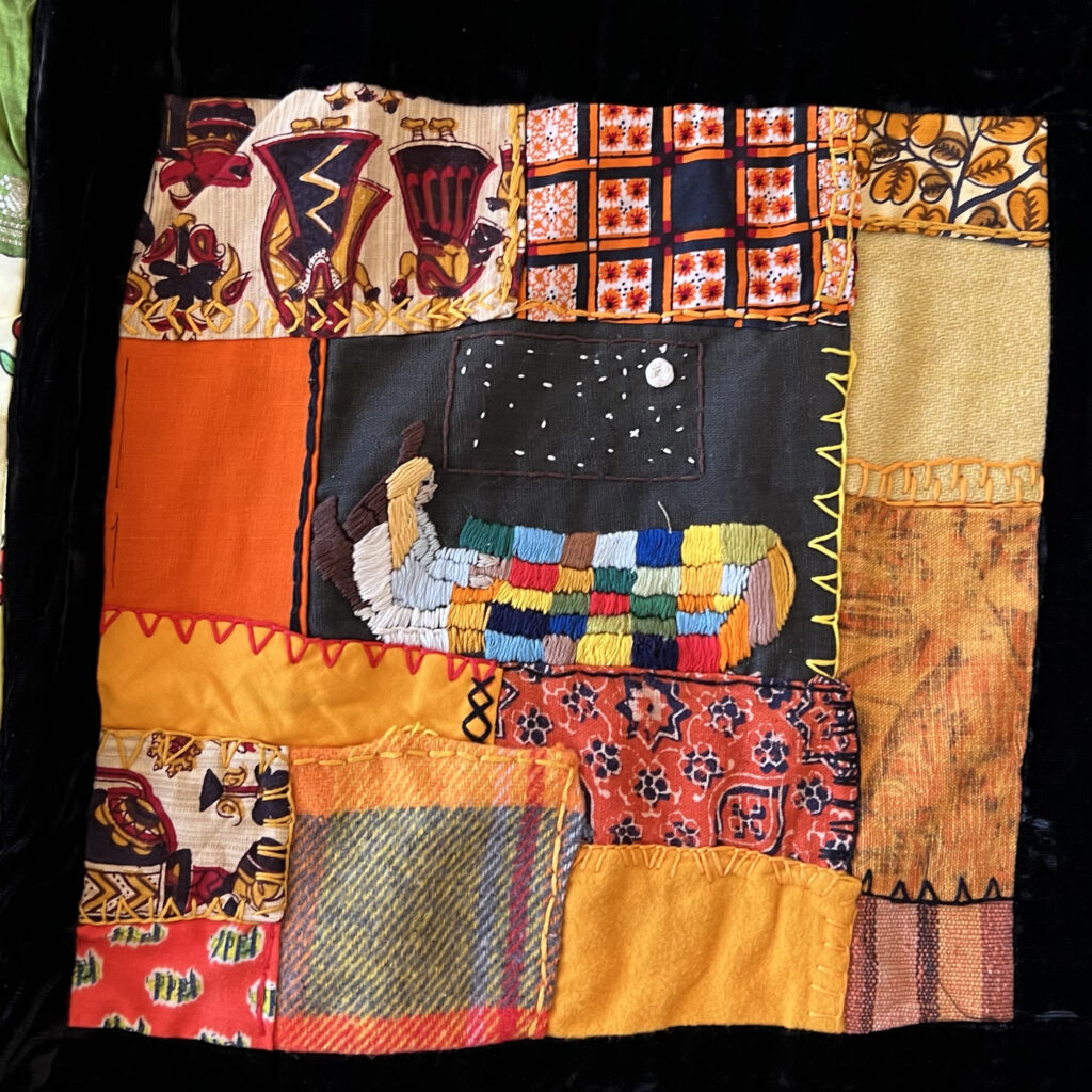 a quilt block in oranges with my first embroidered scene - myself sitting up in bed with a patchwork quilt near a big window with a moon and stars