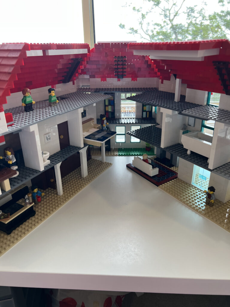 a large Lego house. Its front section is hinged to two wings that swing out to reveal the interior, which is furnished with kithen, bed, sofa, etc.